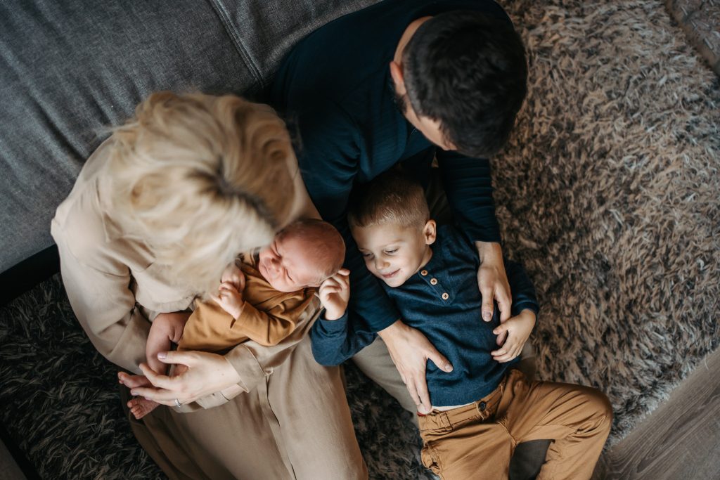 Novorozenec se svým starším sourozencem a rodiči při newborn focení doma v Praze