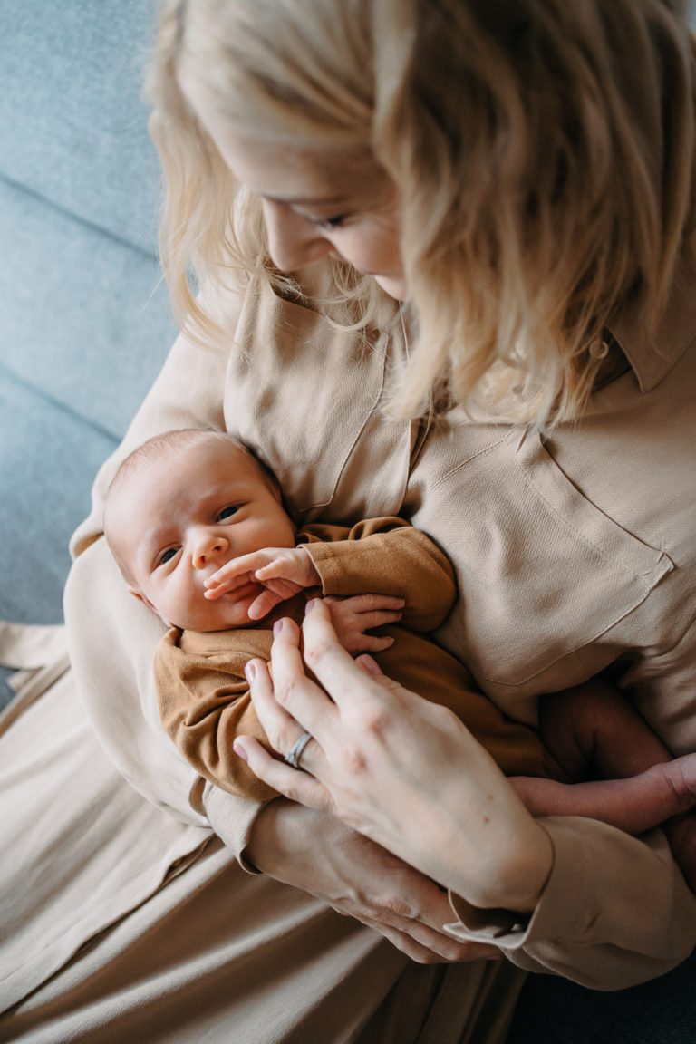 Novorozenec v náručí maminky při newborn focení doma v Praze